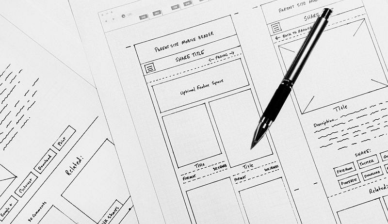 Paper wireframe sketches showing page regions and content placeholders