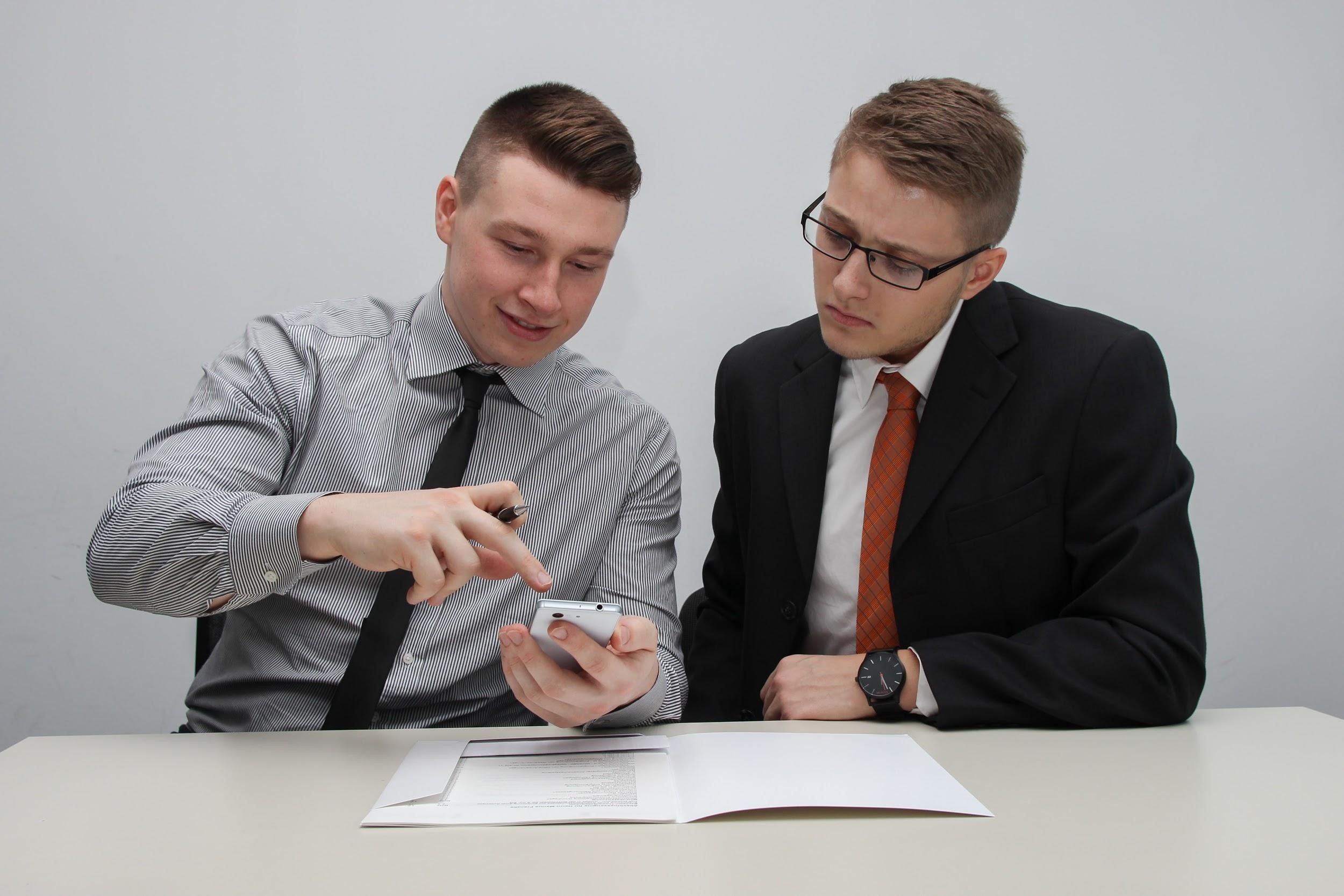Illustrative photograph of two people discussing a mobile screen